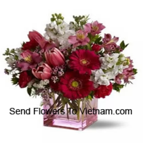 Rose rosse, tulipani rossi e fiori assortiti con riempitivi stagionali disposti in modo splendido in un vaso di vetro
