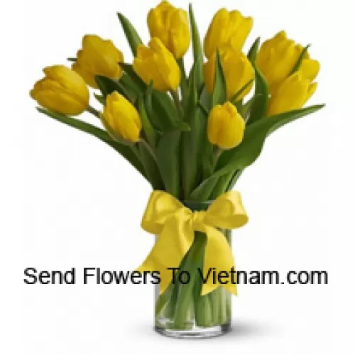 Tulipani gialli con riempitivi stagionali e foglie in un vaso di vetro - Si prega di notare che in caso di non disponibilità di determinati fiori stagionali, gli stessi verranno sostituiti con altri fiori dello stesso valore