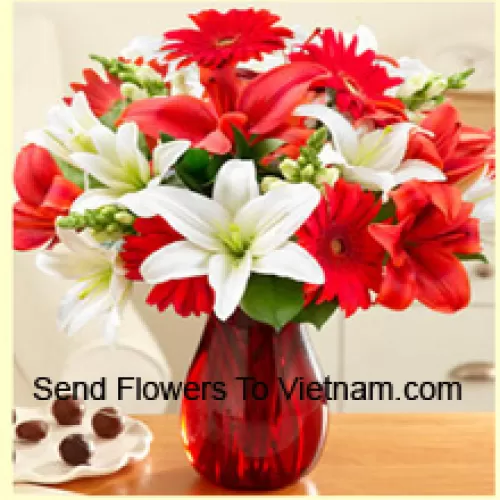 Gerbere rosse, gigli bianchi, gigli rossi e altri fiori assortiti disposti splendidamente in un vaso di vetro
